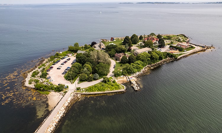 Small island with rich green wildlife and minimal buildings. 
