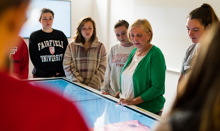 Biology professor showing students something on a large interactive touchscreen.