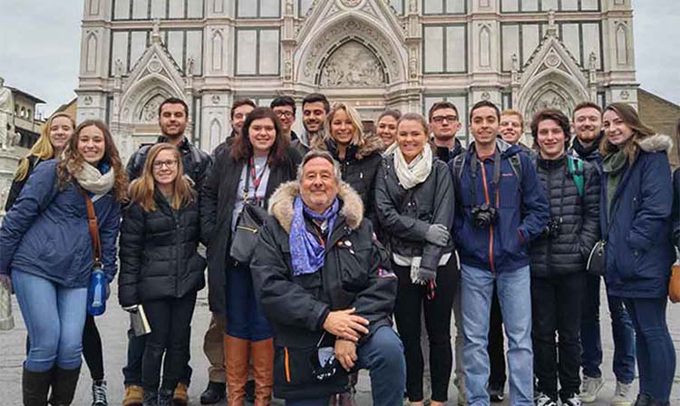Image of a group of smiling people poses together in front of a grand cathedral, capturing a joyful moment.