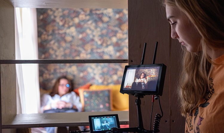 Film, theater, and media arts students recording a short film in a makeshift bedroom set.