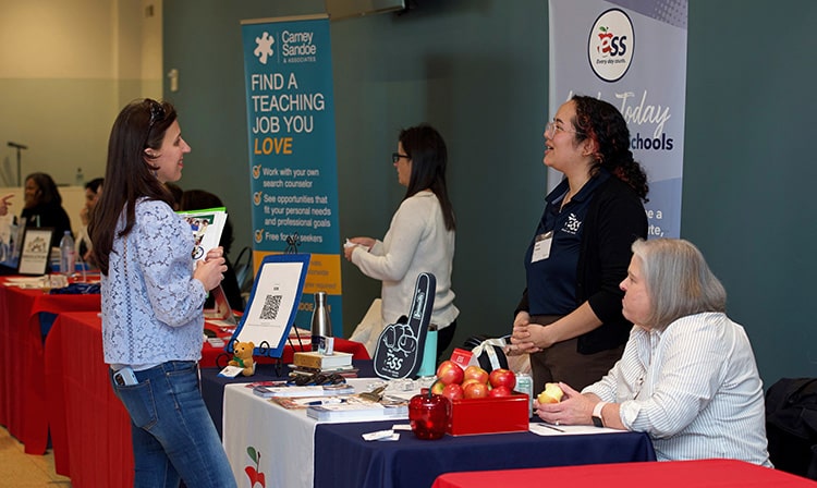 Education master's candidate interacting with ESS K-12 education representatives at a career fair.