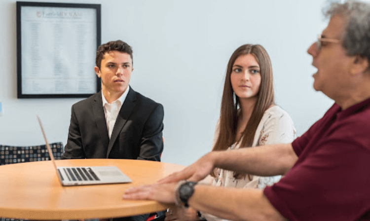  Professor carl scheraga talks with two business school students.