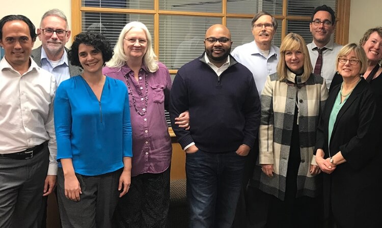 12 faculty members stand in a building.