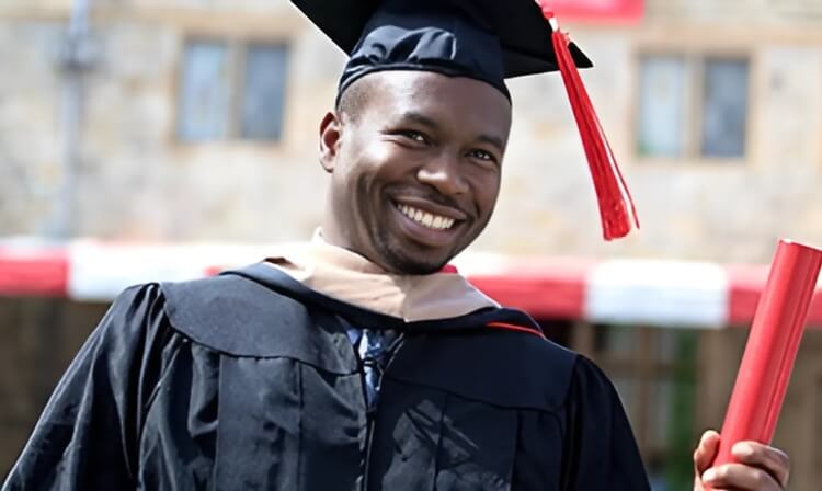 A Fairfield student in a cap and gown holds a diploma tube at graduation.