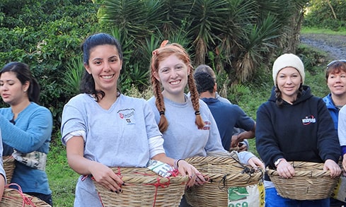 A group of students hold woven baskets outdoors.