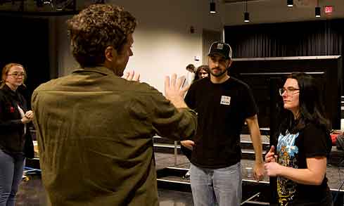 a professor speaks with two students in a tv studio.