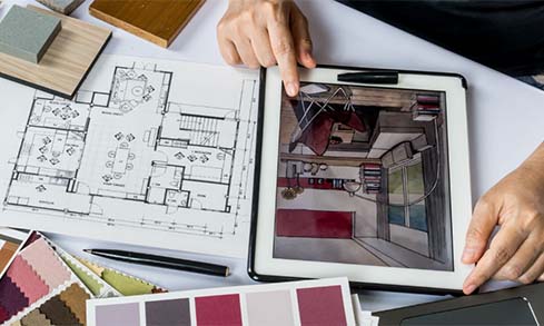 Design student works with ipad and schematics on table. 