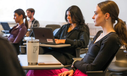 Students sit at desks in a classroom.