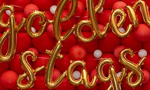 Golden balloons spell Golden Stags in front of a wall of red and white balloons.