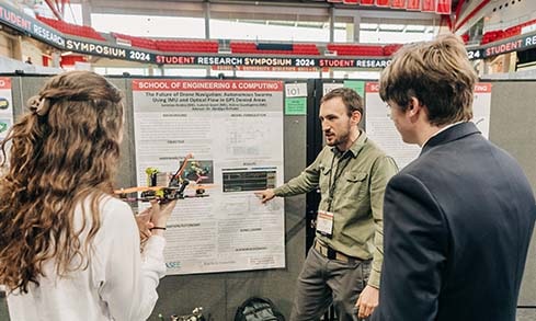 A student presents his poster titled “The Future of Drone Navigation: Autonomous Swarms Using IMU and Optical Flow in GPS Denied Areas”.
