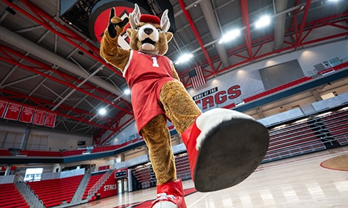 Worm's eye view of Lucas stepping towards the camera as he poses on the Convocation Center basketball court.