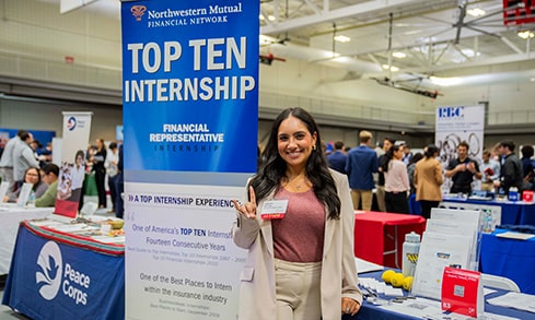 Fairfield alumni representing her company with its 'Top Ten Internship' banner at the Career Fair.