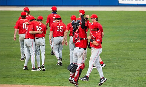 Two baseball players high-fiving each other as the whole team exits the field after a game.