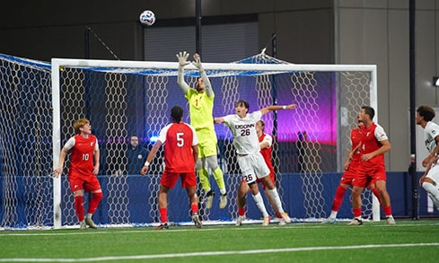 A goalie in yellow jumping to defend Fairfield's goal during a game against UCONN.