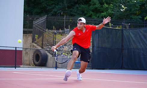 Action shot of a men's tennis player during practice as he lunges to return the ball.