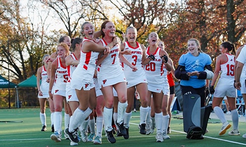 Female student-athletes gathering to celebrate their victorious field hockey game.