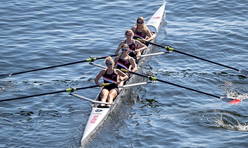 Rowing action shot of a four-woman crew boat during practice.