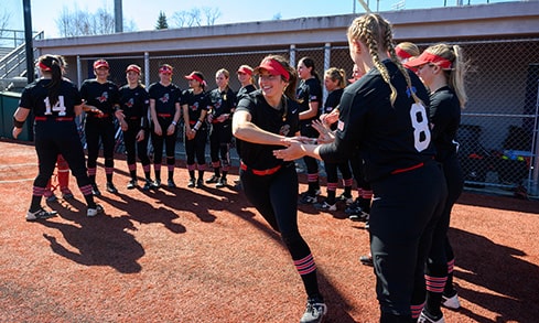 Softball team leader high-fiving her teammates in the dugout before a game.