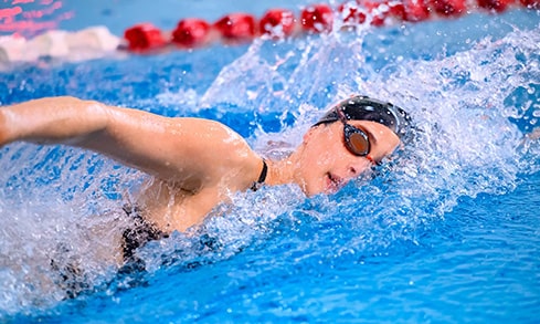 Swim meet action shot of a female student-athlete during her freestyle lap.