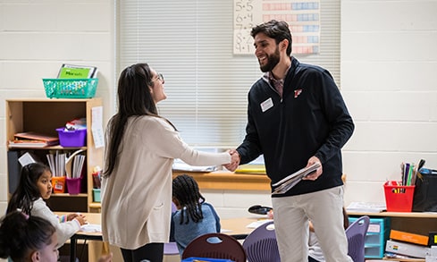 Fairfield staff member meeting with and shaking the hand of a local elementary school teacher in her classroom.