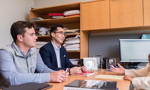 Two finance students meeting with a professor during her office hours to go over a project.
