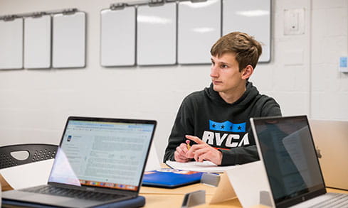 Financial technology student sitting in a study room with a fellow classmate as they collaborate on a project.