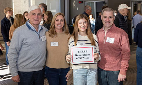 A multi-generational family of Stags (a current student with her parents and grandfather) posing at a Legacy Association event for Stag families to mingle with one another.