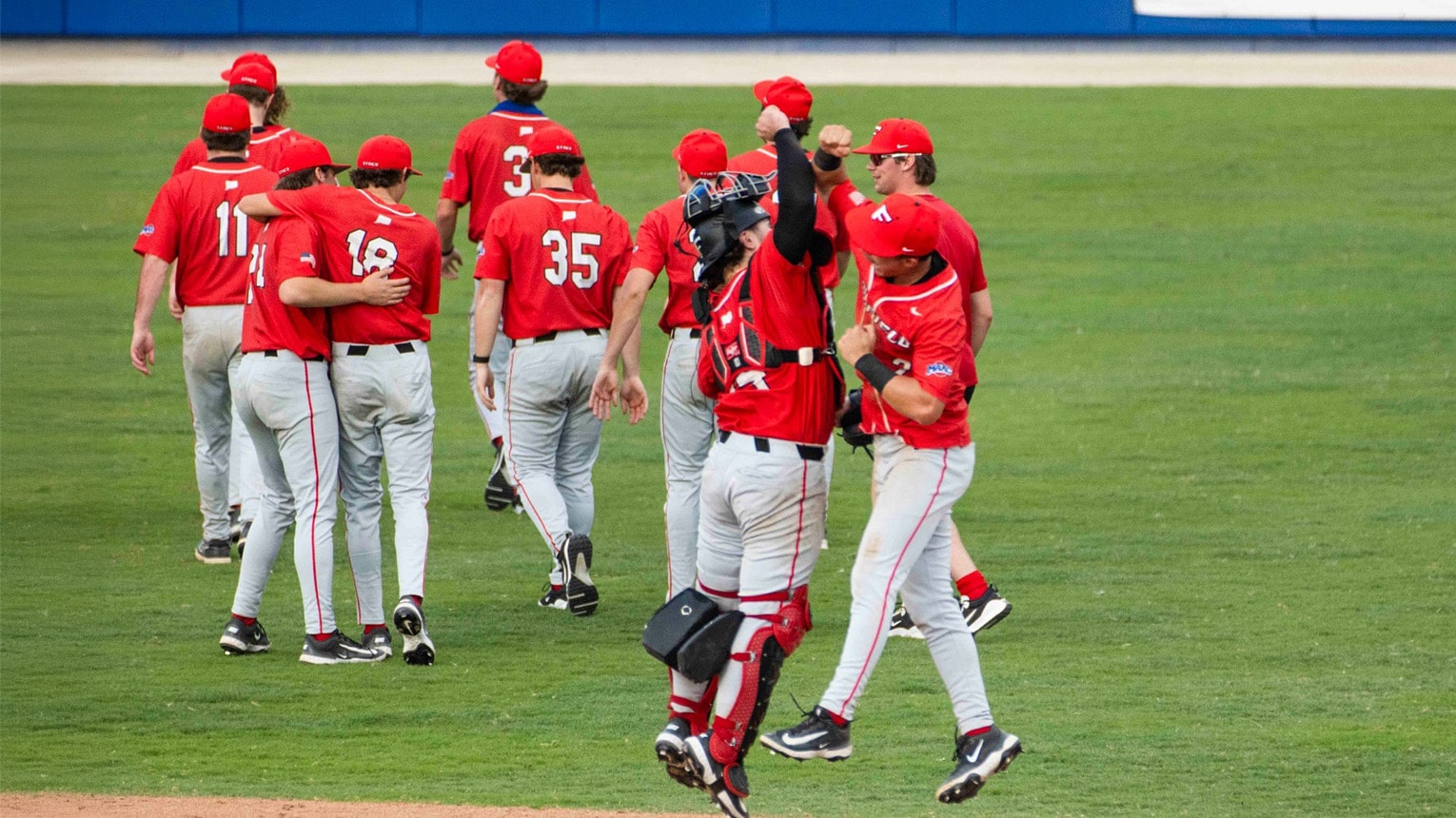 Two baseball players high-fiving each other as the whole team exits the field after a game.