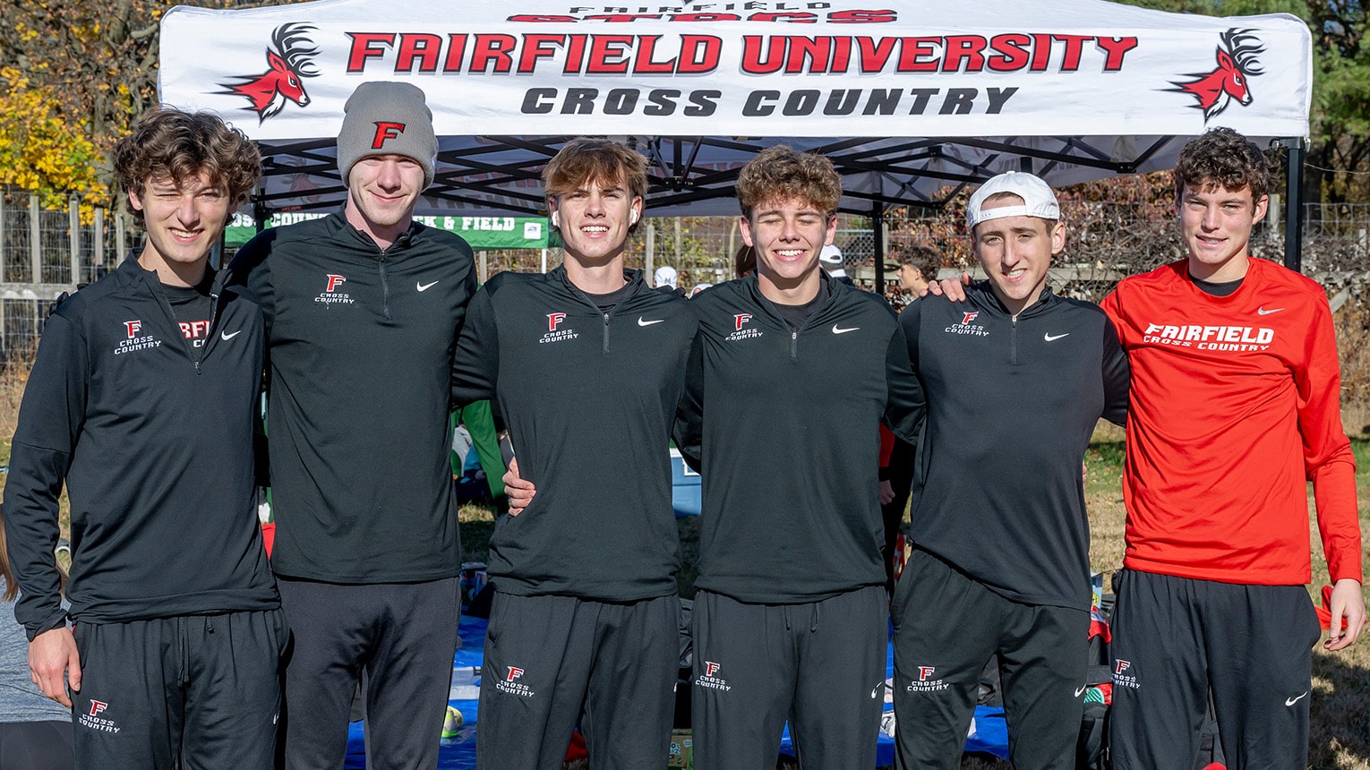 Male student-athlete cross country members posing together at a campus sports fair.