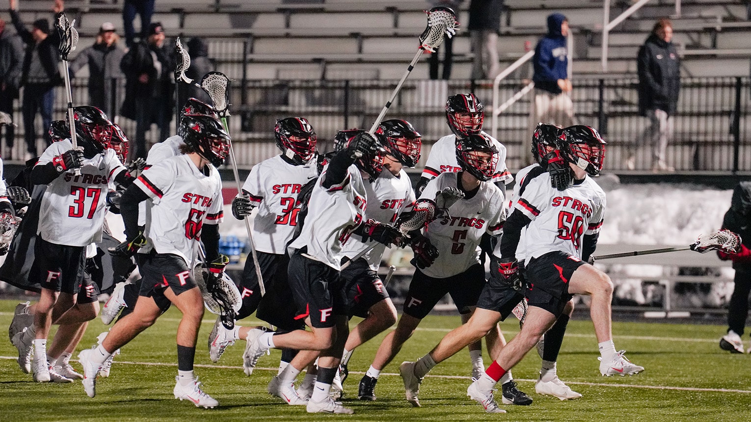 Men's lacrosse team yelling and charging onto the field, eager to begin their game.
