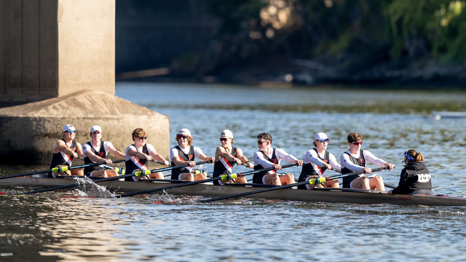 A crew boat of eight with the coach at the helm glides along the water during practice.