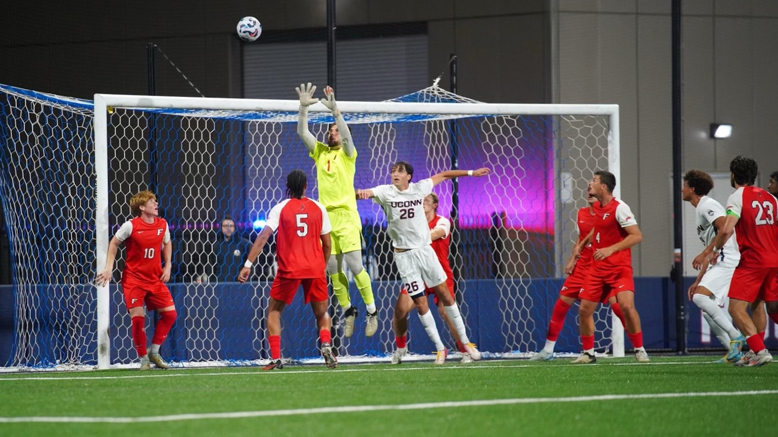 A goalie in yellow jumping to defend Fairfield's goal during a game against UCONN.