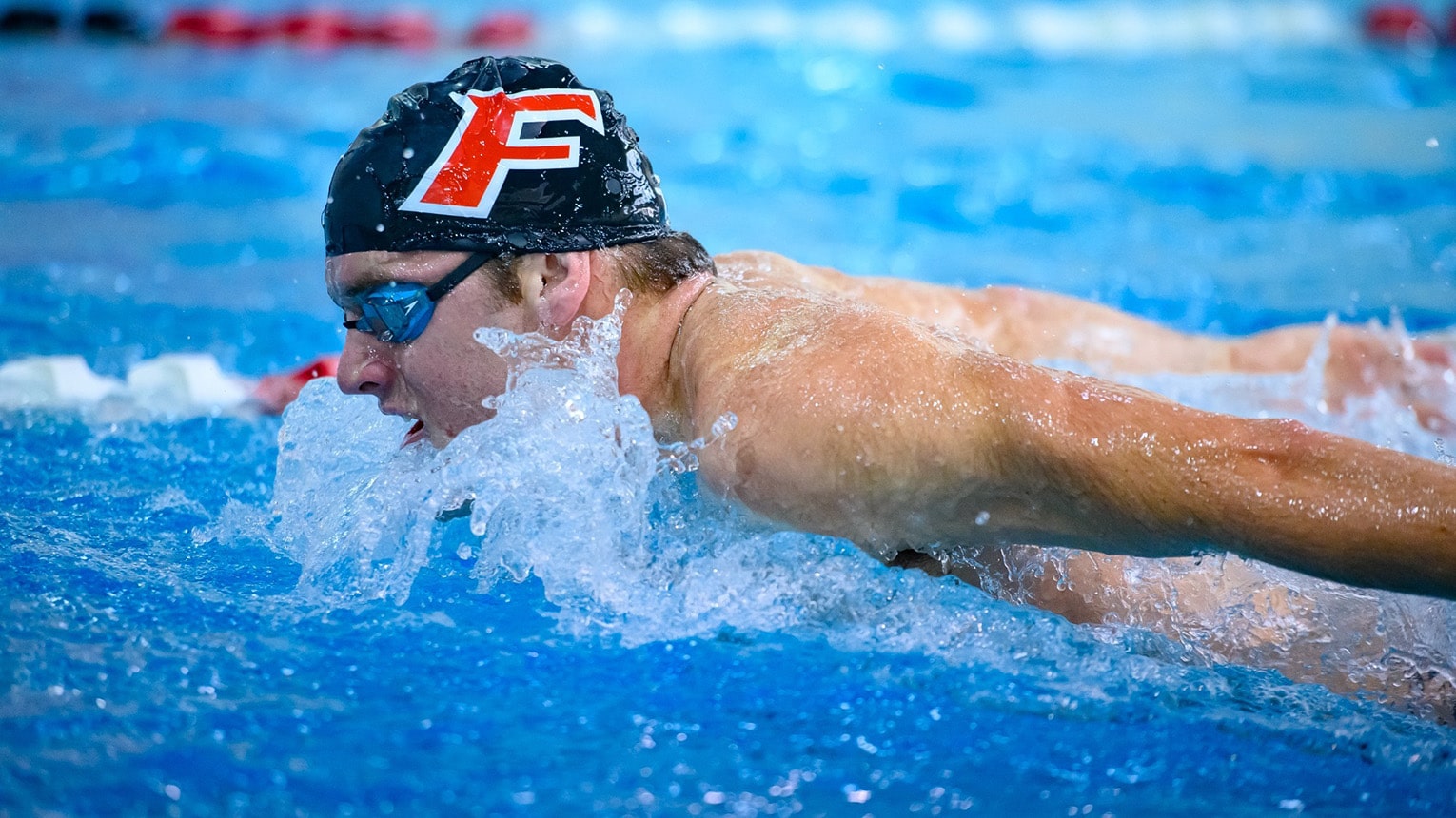 Swim meet action shot of a male student-athlete during his butterfly lap.