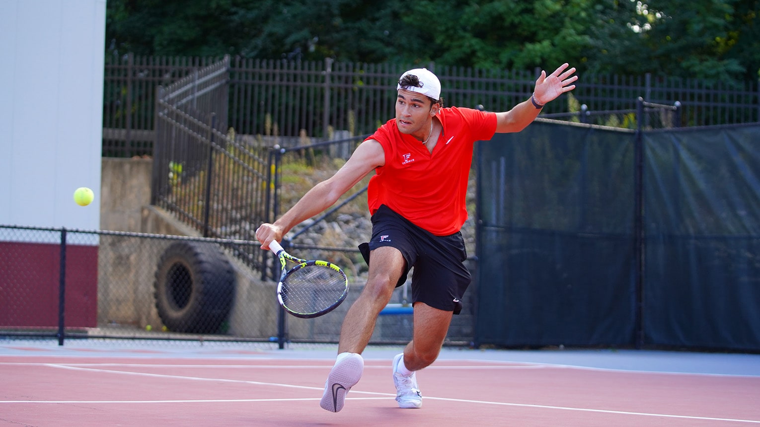 Action shot of a men's tennis player during practice as he lunges to return the ball.