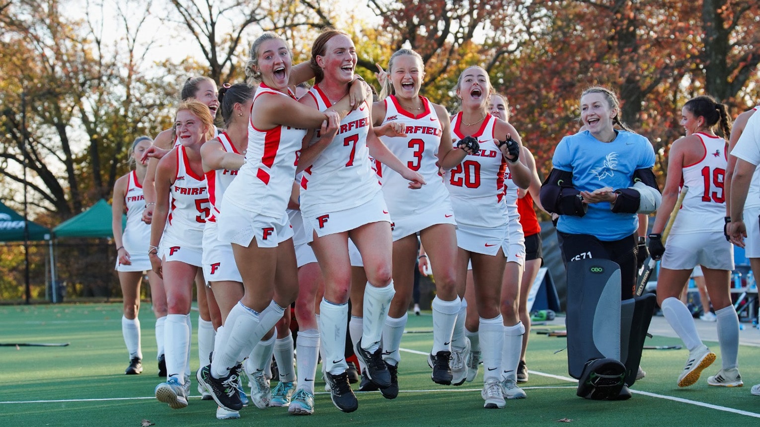 Female student-athletes gathering to celebrate their victorious field hockey game.