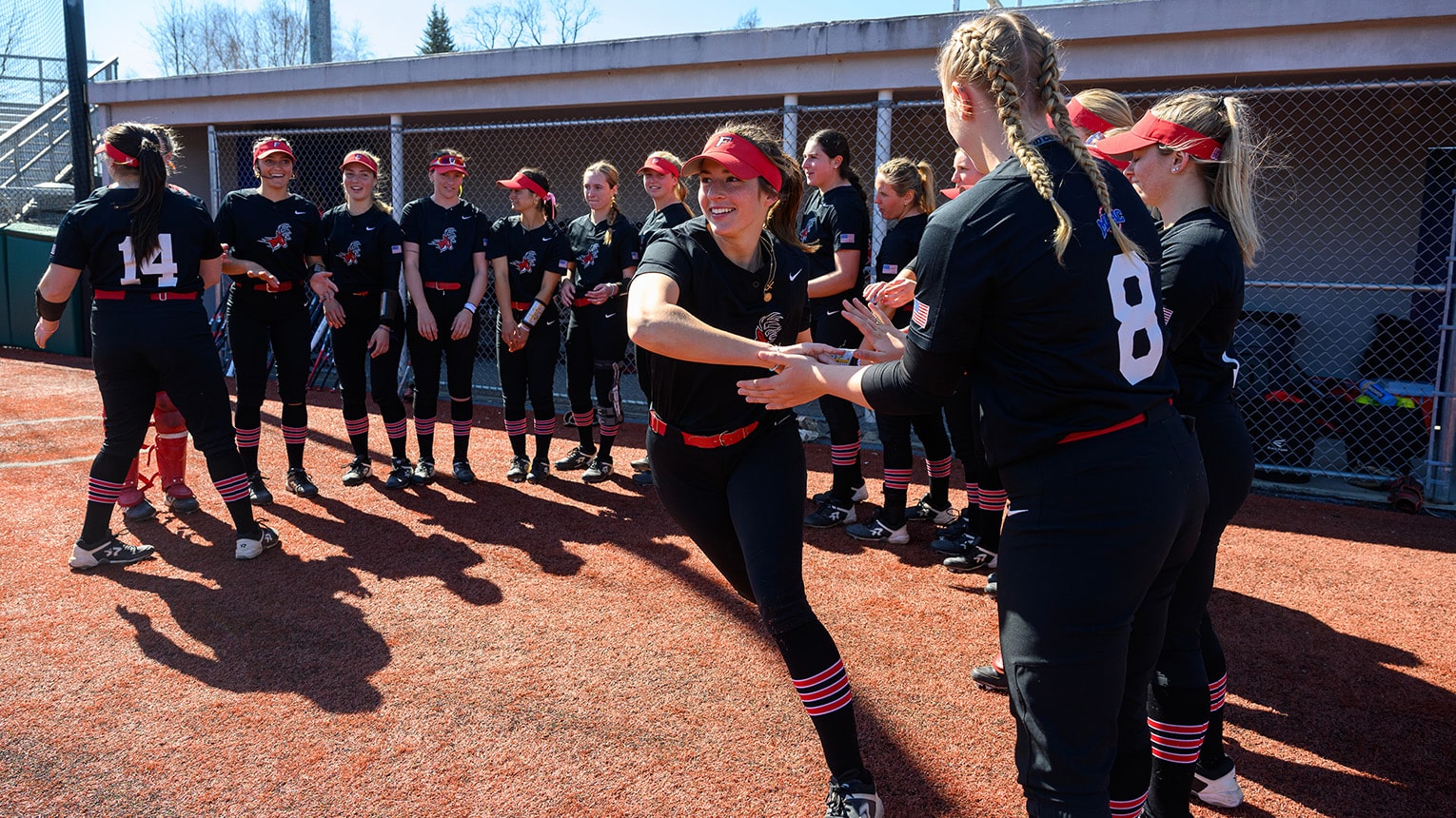 Softball team leader high-fiving her teammates in the dugout before a game.