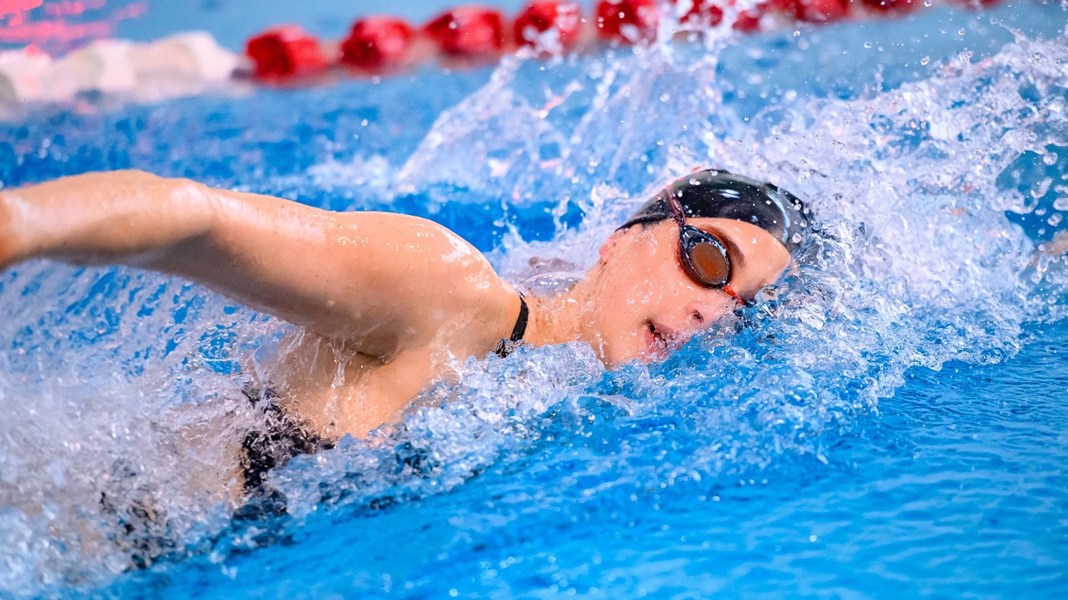 Swim meet action shot of a female student-athlete during her freestyle lap.
