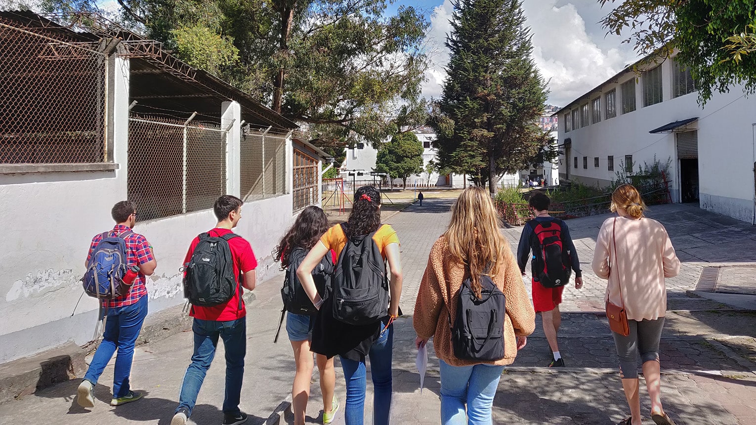 Students walking in a group on a bright, sunny morning to their designated immersion trip service place.