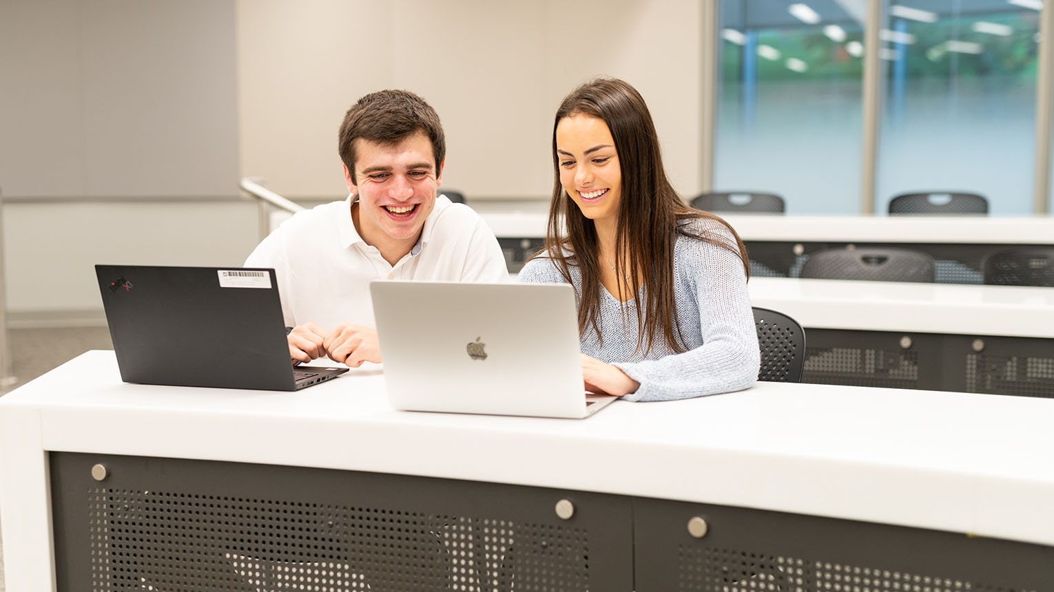 Two students doing work together on their laptops in a Dolan lecture classroom.