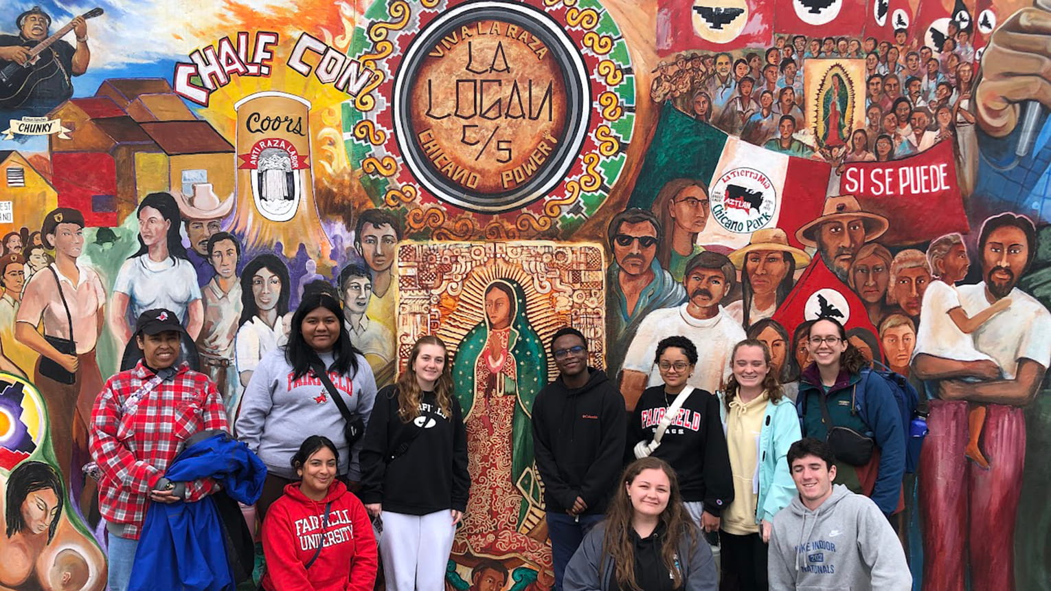 A group of students stands outdoors in front of a cultural mural in San Diego.