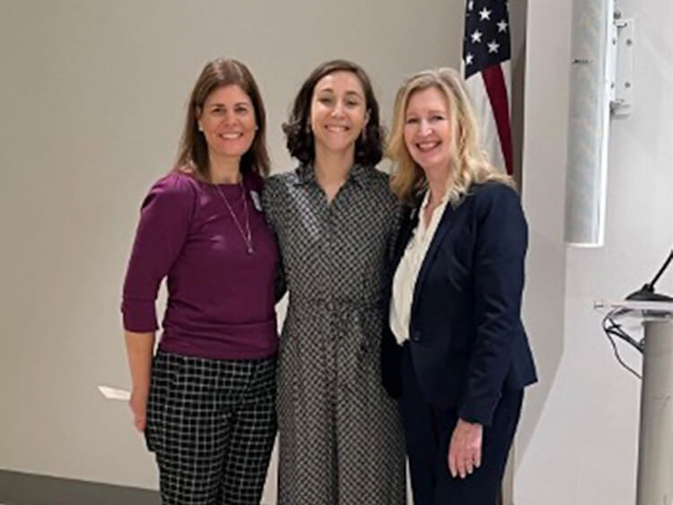 Three women standing together smiling. 