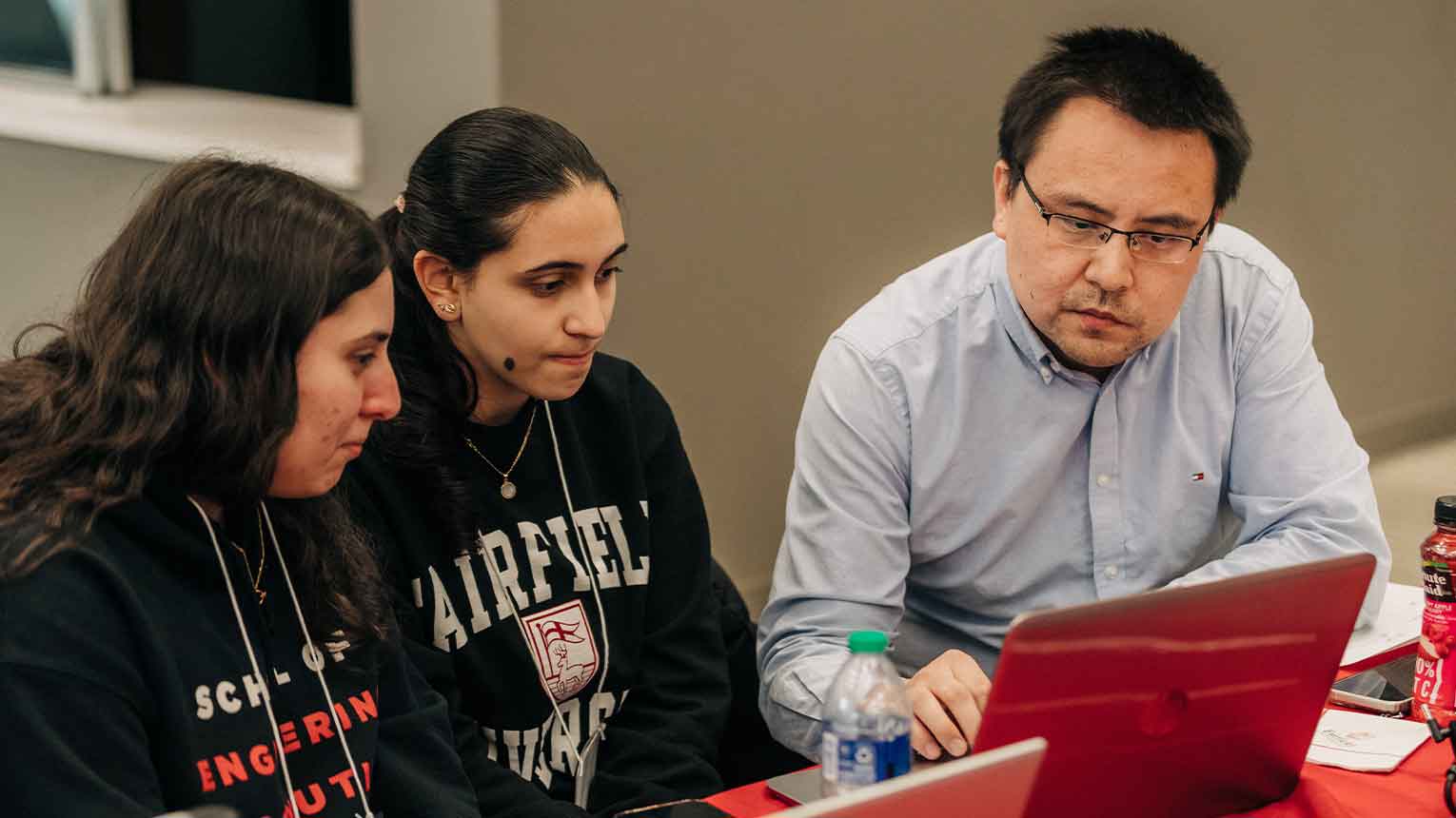 Two students with a professor at the StagHack competition.