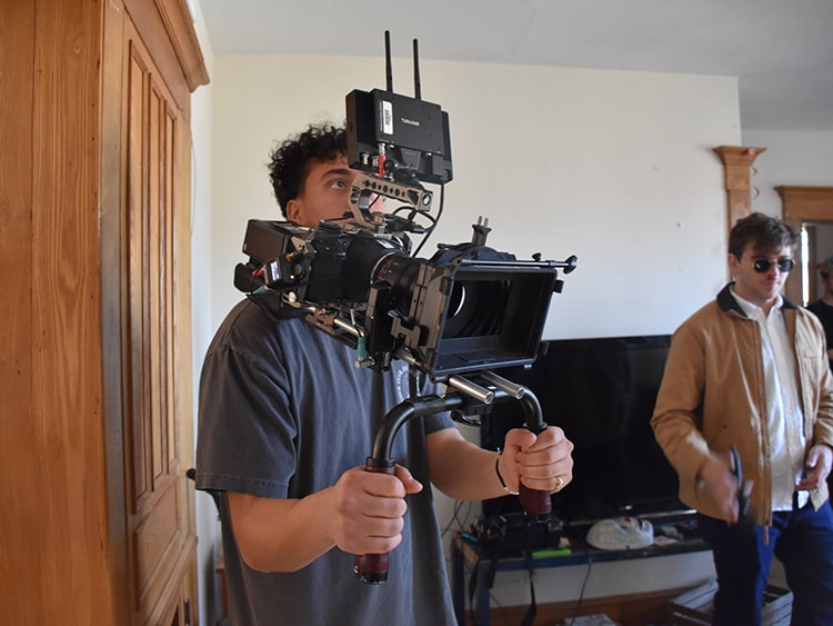 Male student holding a professional film camera with a set of steady bars.