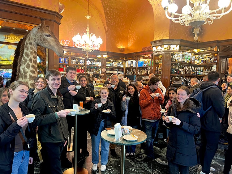 Fairfield students and professor smiling and posing with cappucinos in a local Italian coffee shop.