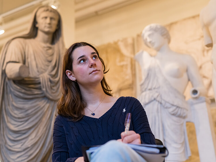A woman sitting before a statue, reflecting on its artistic details.