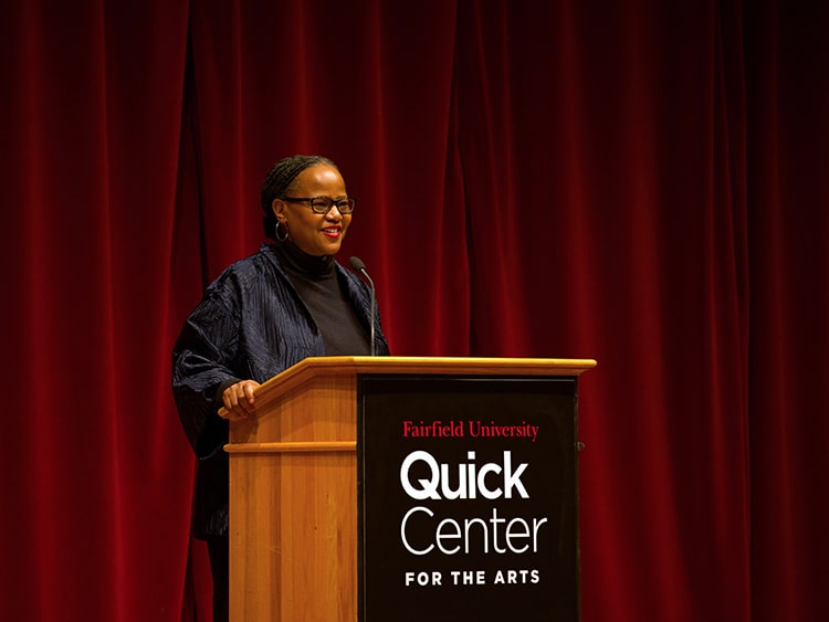 Novelist giving her speech at a Fairfield-branded podium during the annual Martin Luther King Jr. Convocation.