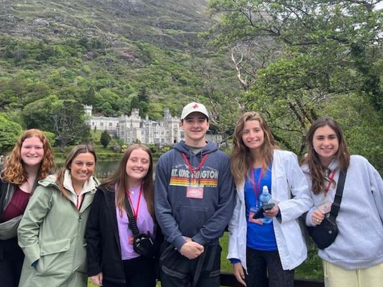 Students posing in front of a castle structure and river in Galway, Ireland.