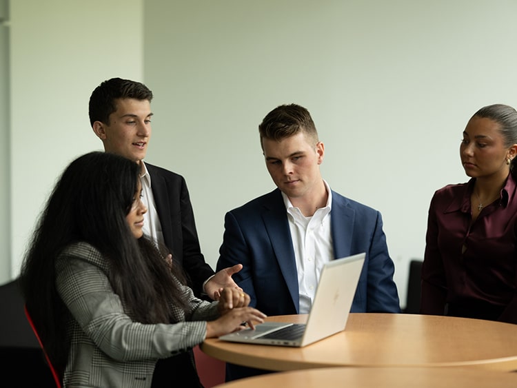 Business students collaborating at a study table while one student takes notes.
