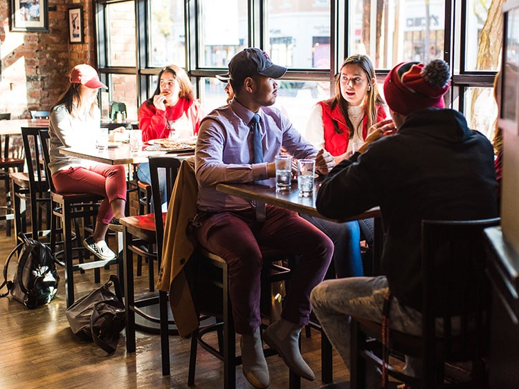 Fairfield students eating lunch at a bar table in a local pizza place.