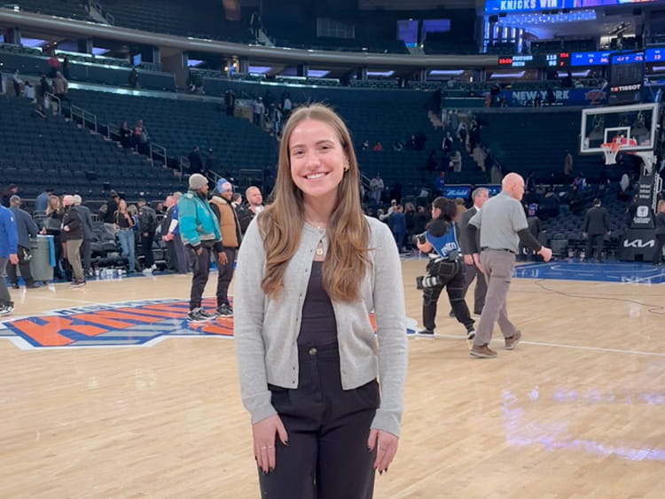 Sports Media major student standing proudly on a basketball court in her role as a production assistant.